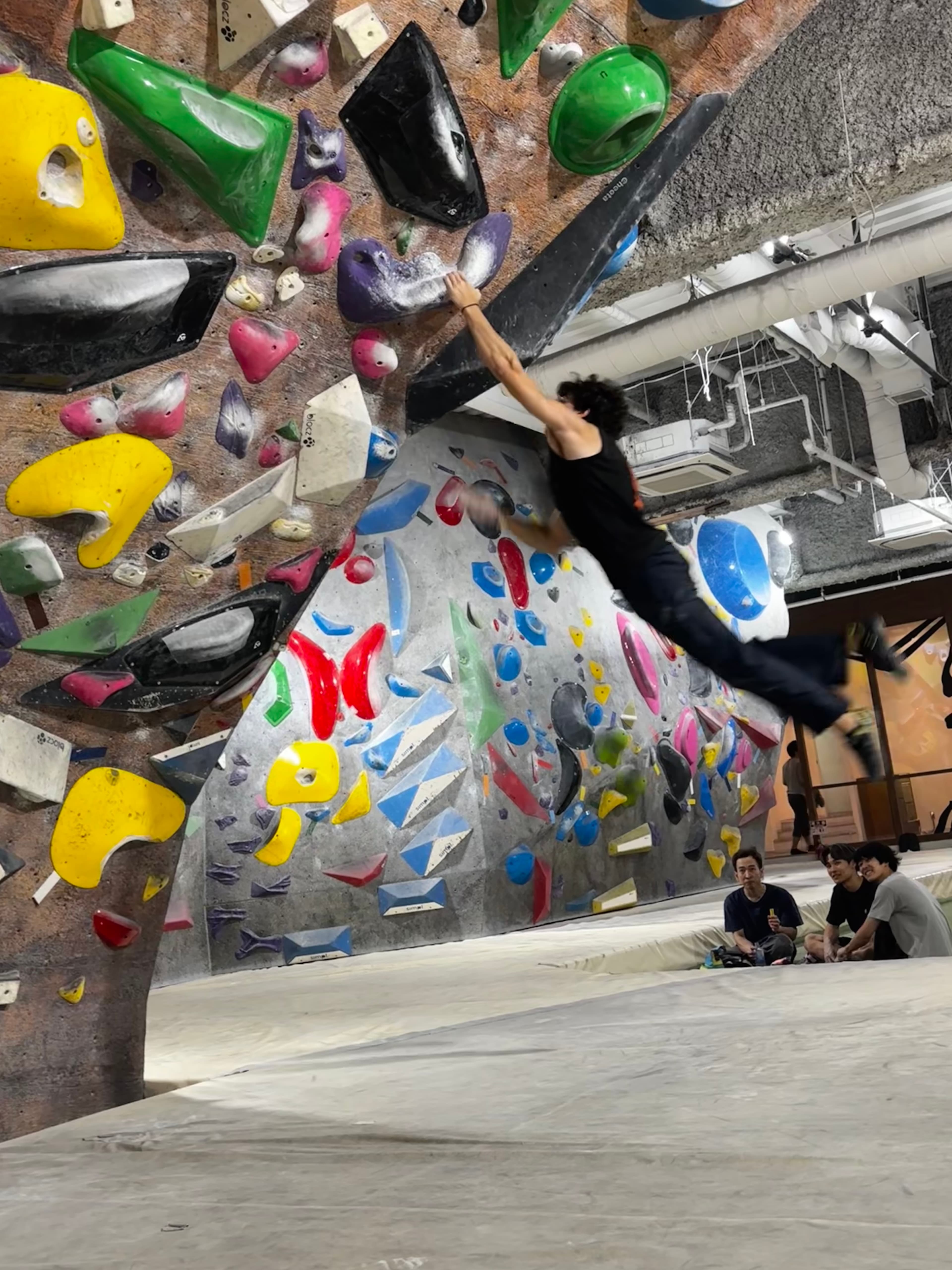 Matias on the bouldering wall, feet off, fully committed to the next move.