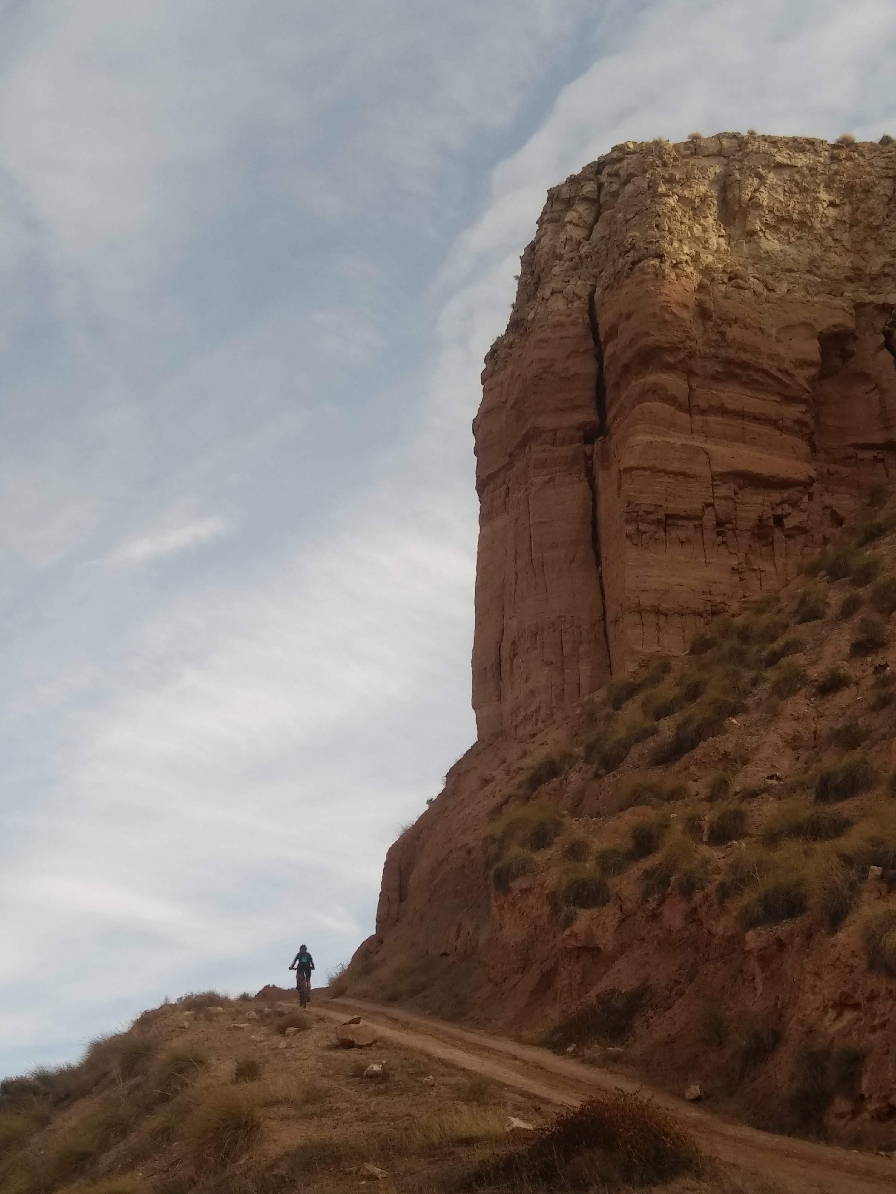 A solo rider beneath a red sandstone tower